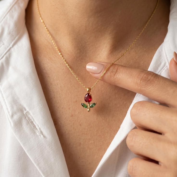 Gold necklace with a red gemstone pendant worn by a person