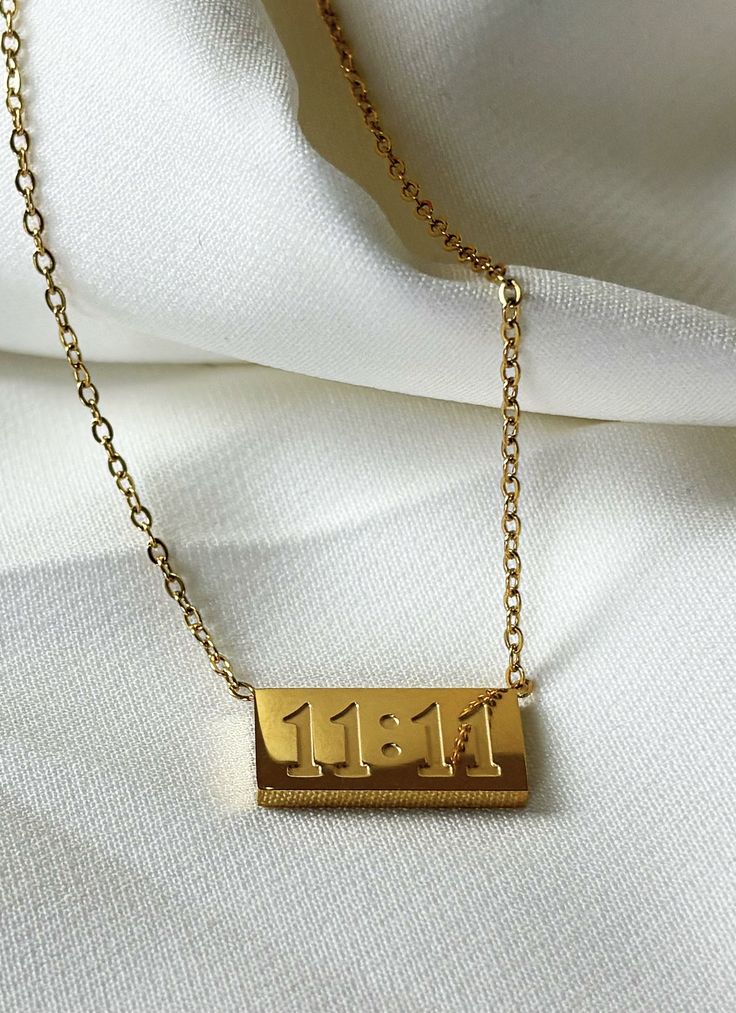 Gold necklace with a rectangular pendant on a white fabric background